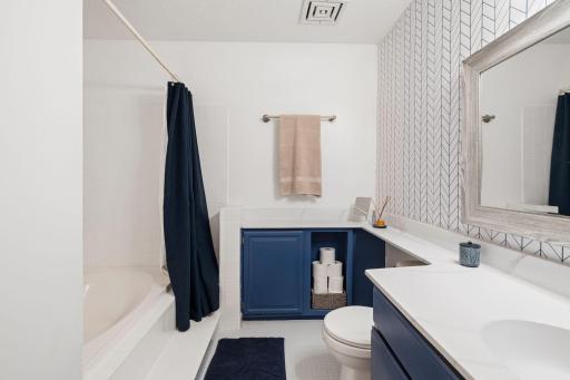 Additional view showcasing the bathroom's extensive countertop space, built-in storage, and tub/shower area.