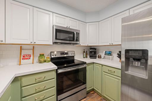 Stainless-steel appliances complement the two-tone cabinetry and bright finishes throughout the kitchen.