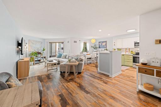 Spacious open-concept main level connecting the living room, dining area, and kitchen with abundant natural light and warm flooring..