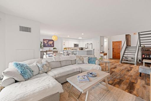 Reverse view of the main level showcasing the spacious living room with sightlines to the dining area, kitchen, and entry.