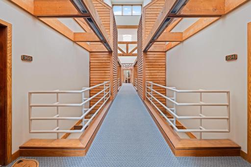 Distinctive interior corridor with exposed wood beams, skylights, and open architectural details leading directly to Unit 305.