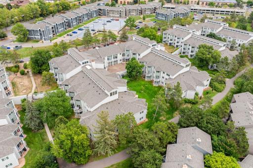 Aerial view of the Maclaren Hill condominium community surrounded by mature trees, green space, walking paths, and neighboring residences.