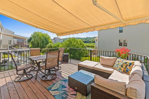 A custom retractable awning provides added shade, while stairs lead to a paver patio below