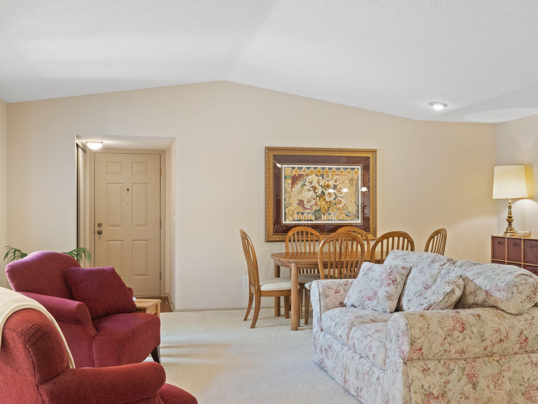 Light and bright living room has nuetral carpet and vaulted ceiling.