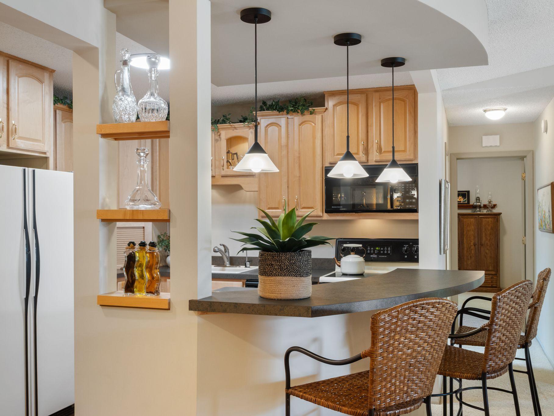 Kitchen combines good looks with practical storage and decorative display shelving and spacious breakfast bar.