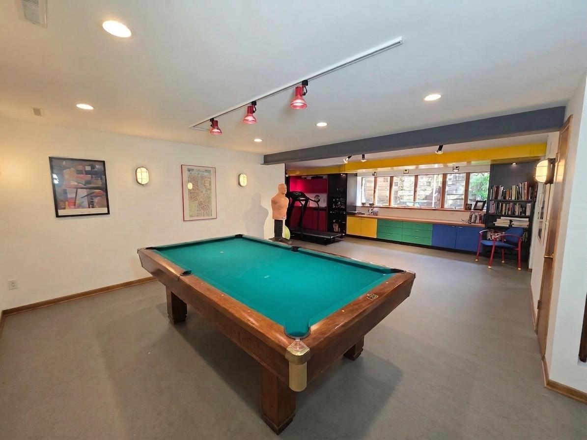 Impressive game and recreation room with billiards area, dedicated fitness space, track lighting, and extensive custom built-ins.