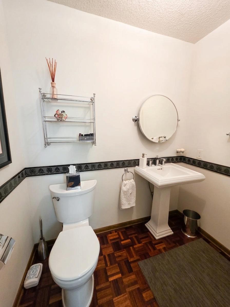Inviting powder room featuring a pedestal sink, hardwood parquet flooring, and timeless architectural details.