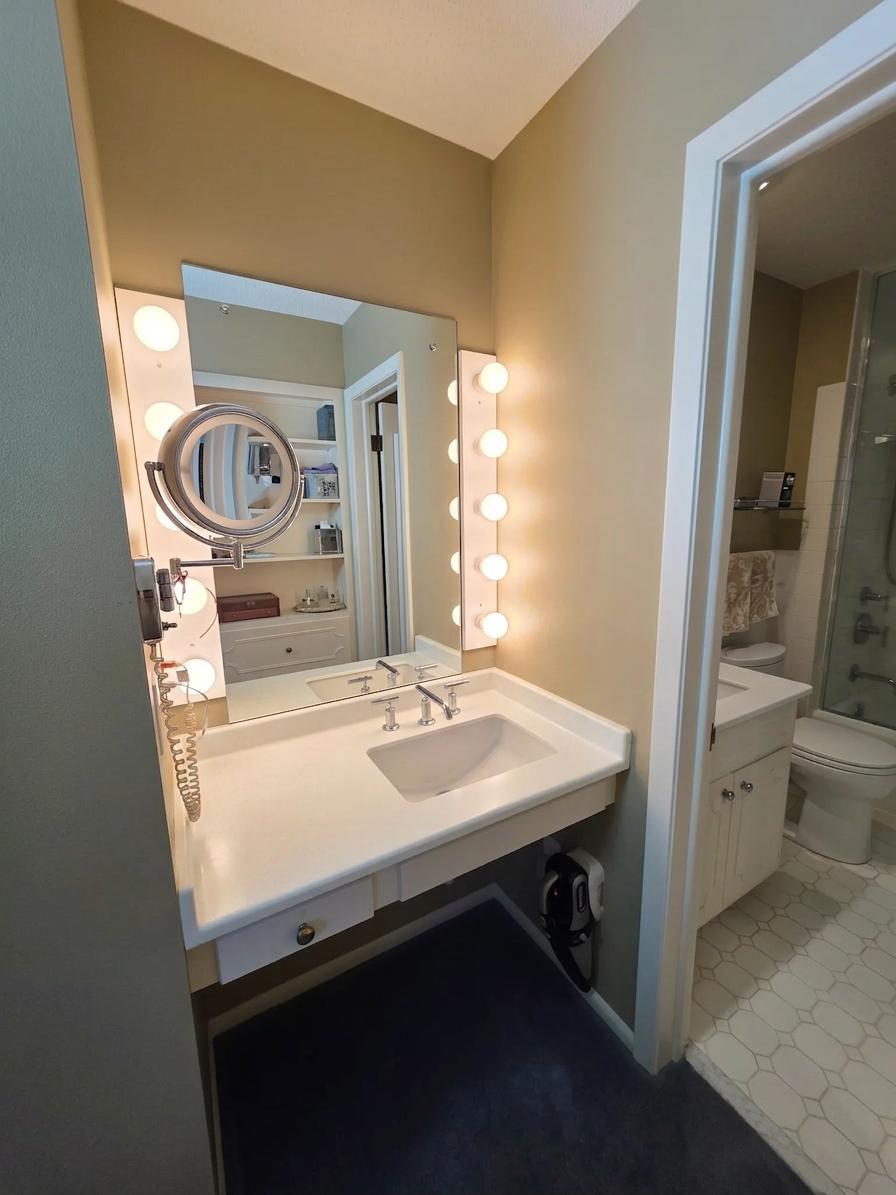 Dedicated dressing and vanity area with illuminated mirror, built-in counter, and convenient access to the adjoining bath.