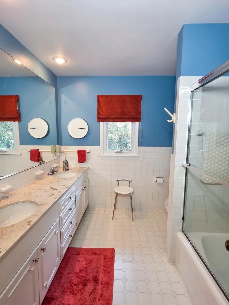 Bright full bath featuring a dual-sink vanity, generous counter space, extensive storage, and a tub/shower combination.