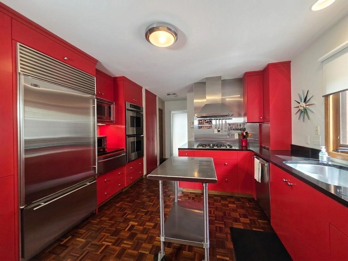 Striking custom kitchen with bold cabinetry, premium stainless-steel appliances, gas cooktop, generous storage, and a stainless work island.