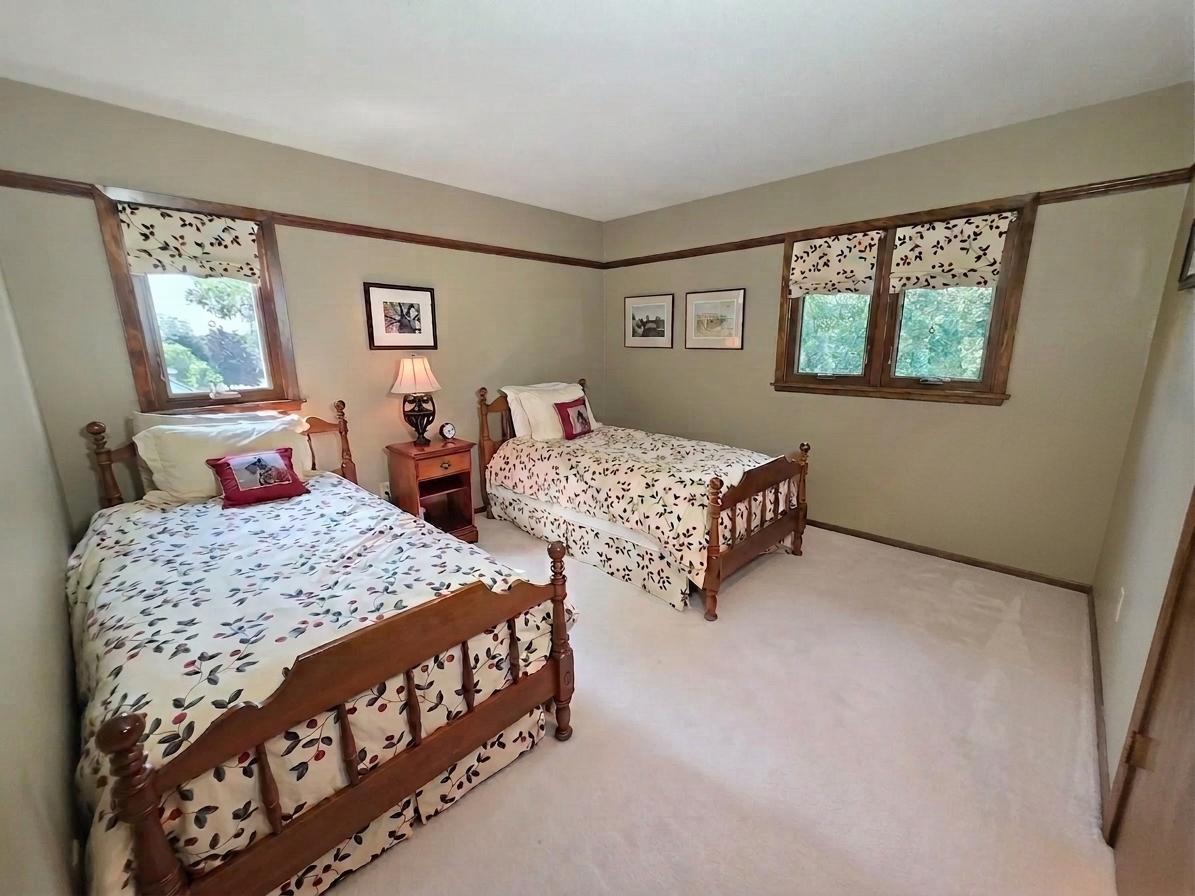 Spacious bedroom with multiple windows, generous floor space, and warm natural wood trim.