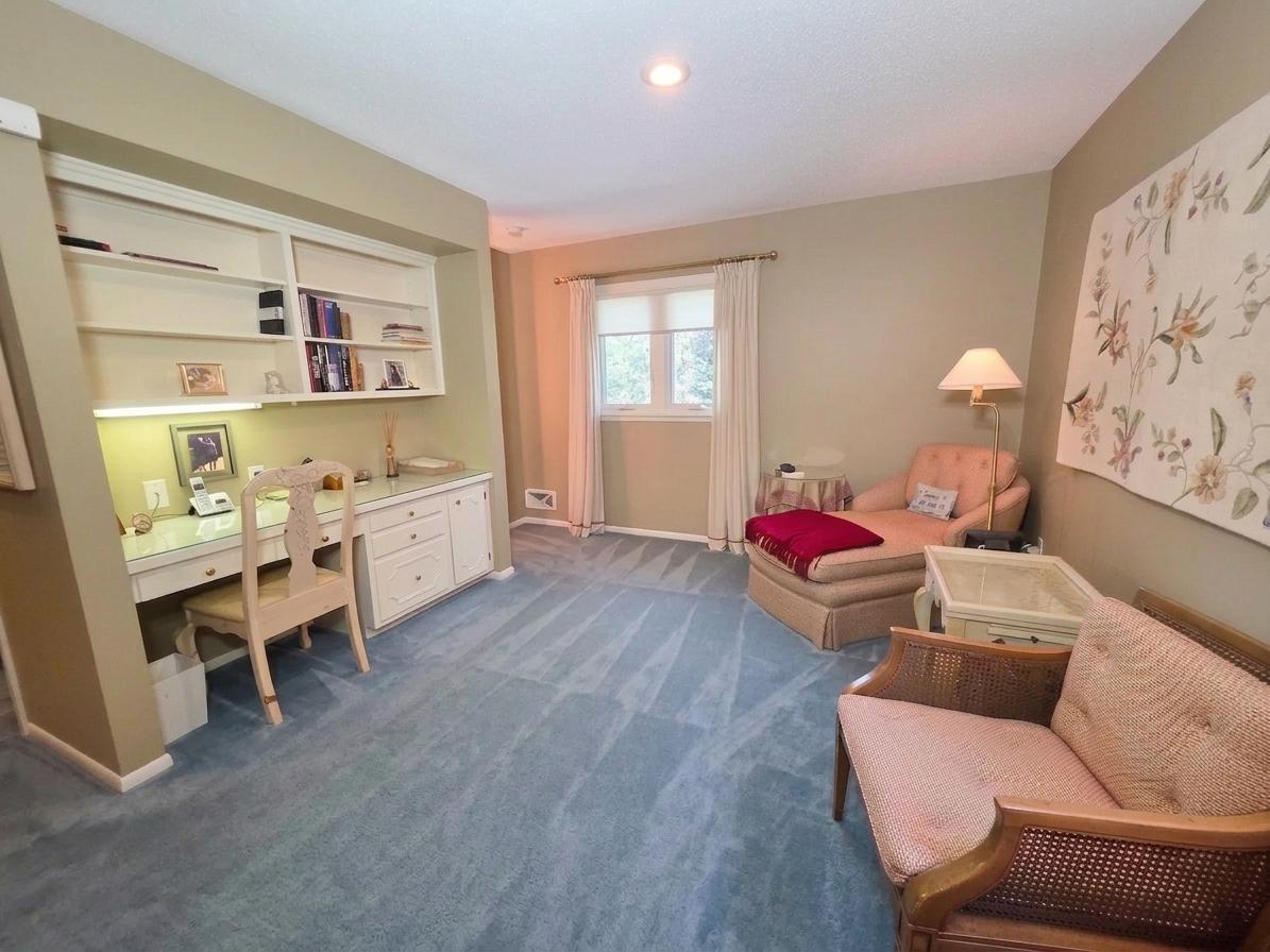 Owner's suite sitting room featuring custom built-in desk and cabinetry, comfortable lounge space, and soft natural light.
