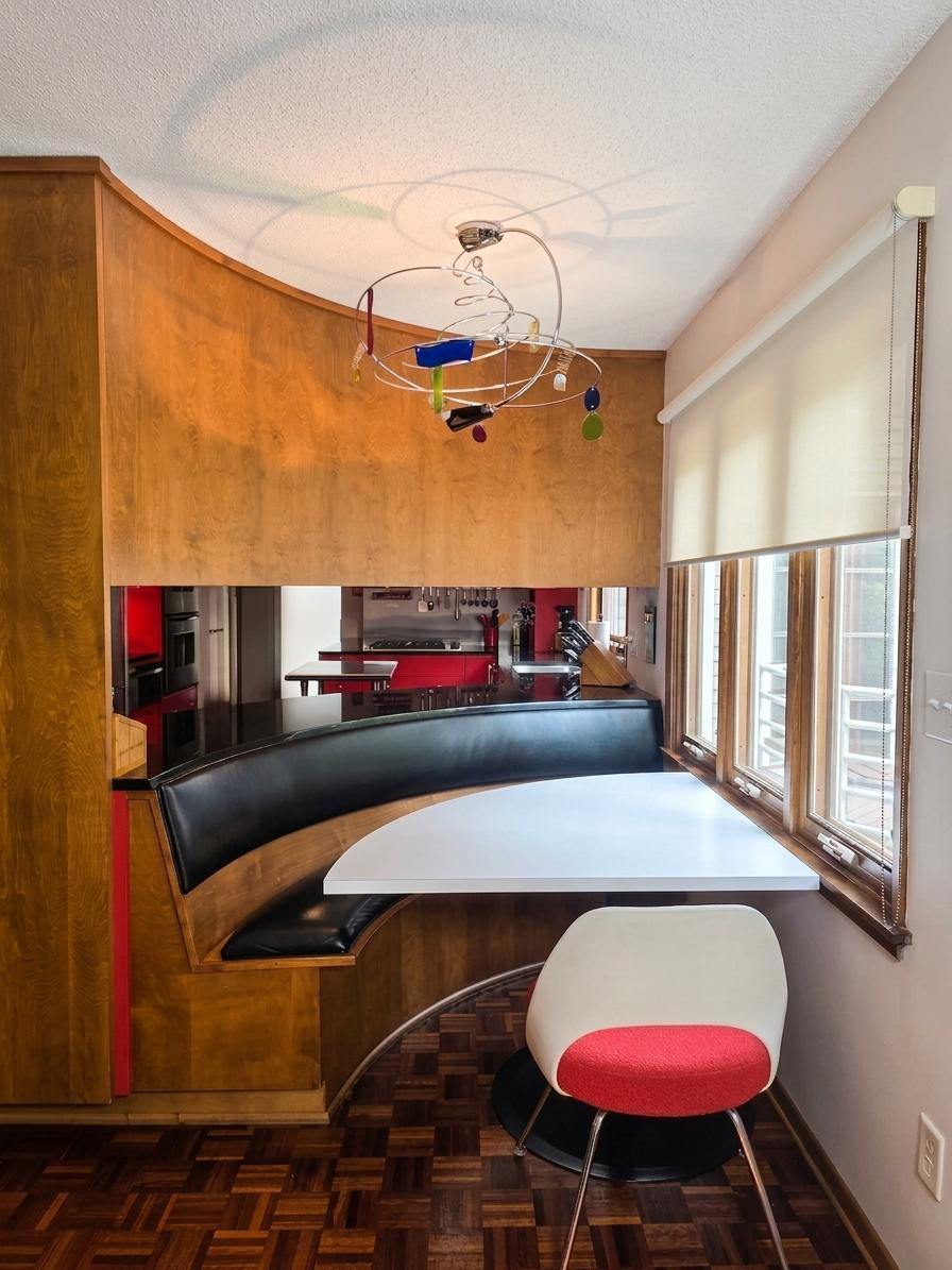 Charming dining area with a custom curved banquette, built-in table, distinctive lighting, and convenient connection to the kitchen.