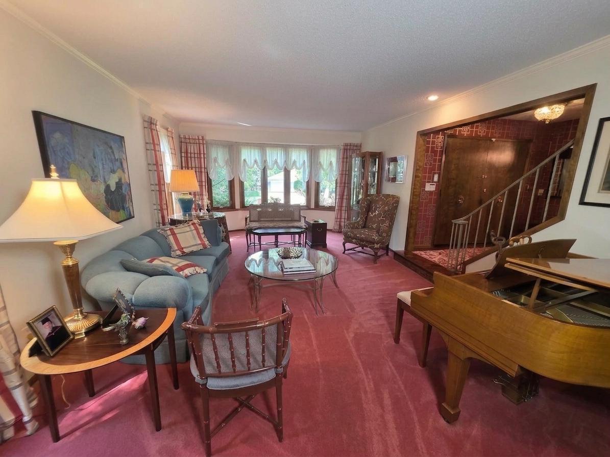 Spacious formal living room with expansive windows, abundant natural light, distinctive millwork, and an open connection to the dramatic entry and staircase.