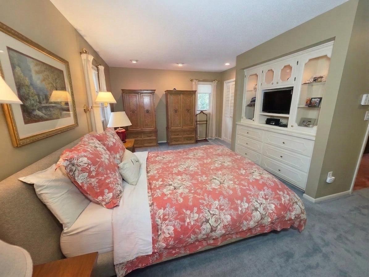Spacious owners' suite with recessed lighting, multiple windows, and extensive custom built-in cabinetry and storage.