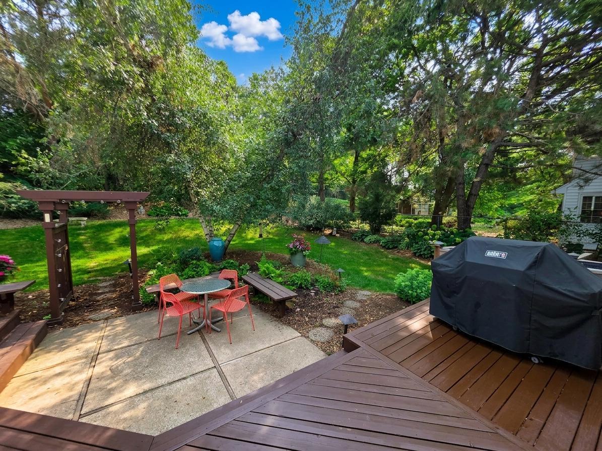 Peaceful backyard retreat with mature trees, garden beds, patio seating, and generous outdoor entertaining space.
