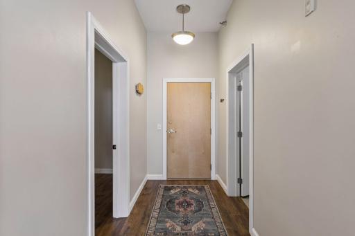 Foyer entry with solid wood door, and wall coat rack.