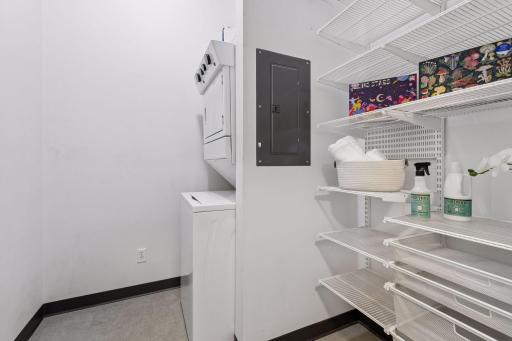 Newer stacked washer and dryer (2023), and built-in storage shelves.