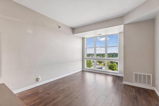 Wall to wall windows and a top-floor view in the open concept living/dining/kitchen area.