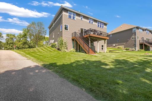 Rear Exterior Perspective: View of the home's low-maintenance vinyl siding, walk-out lower level, elevated maintenance-free deck with staircase, and expansive, manicured side yard.