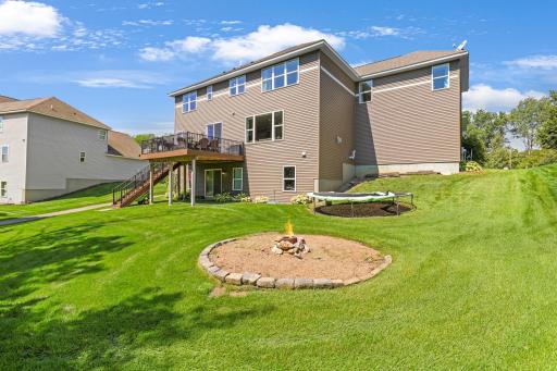 Spacious, sun-drenched backyard featuring a custom stone-ringed fire pit area—perfect for gathering on crisp evenings—plus a large yard for play and recreation.