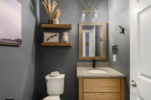 Stylish powder room with charcoal walls, a warm wood vanity, and modern finishes
