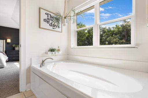 Unwind in the oversized built-in soaking tub, perfectly positioned under a large window to enjoy abundant natural light and peaceful woodland views right from the primary suite.