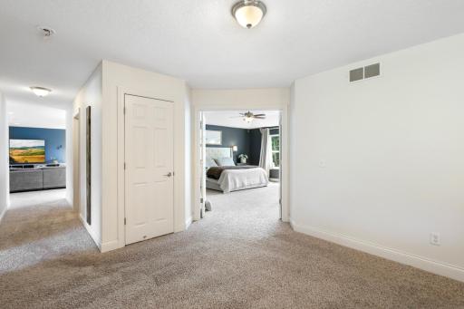 Hallway leading through double doors into the generous primary suite. It offers an effortless layout connecting the upper-level bedrooms and additional living spaces.