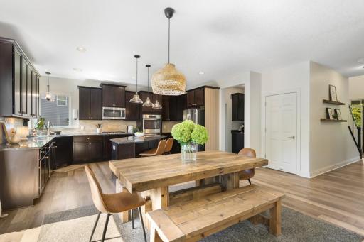 Beautifully updated kitchen with dark cabinetry, stainless steel appliances, large center island, and modern light fixtures. The open layout flows seamlessly into the dining and main living areas.