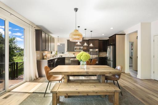 Spacious kitchen and dining area with abundant natural light, updated flooring, stainless steel appliances, and a generous island. Sliding doors offer easy access to the deck and backyard.