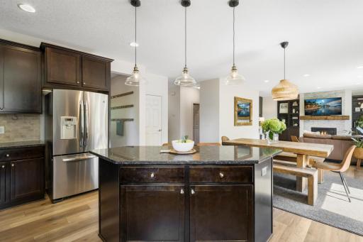 A central kitchen island with stylish glass pendant lighting overlooks the light-filled dining space and cozy living room