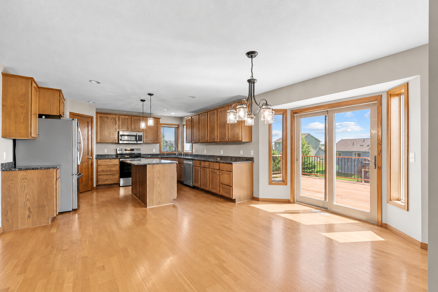 Open-concept kitchen and dining area with hardwood floors and direct access to the deck