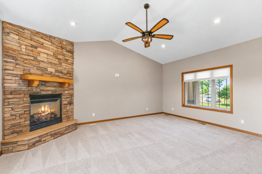 Vaulted great room featuring a striking floor-to-ceiling stone fireplace and abundant natural light