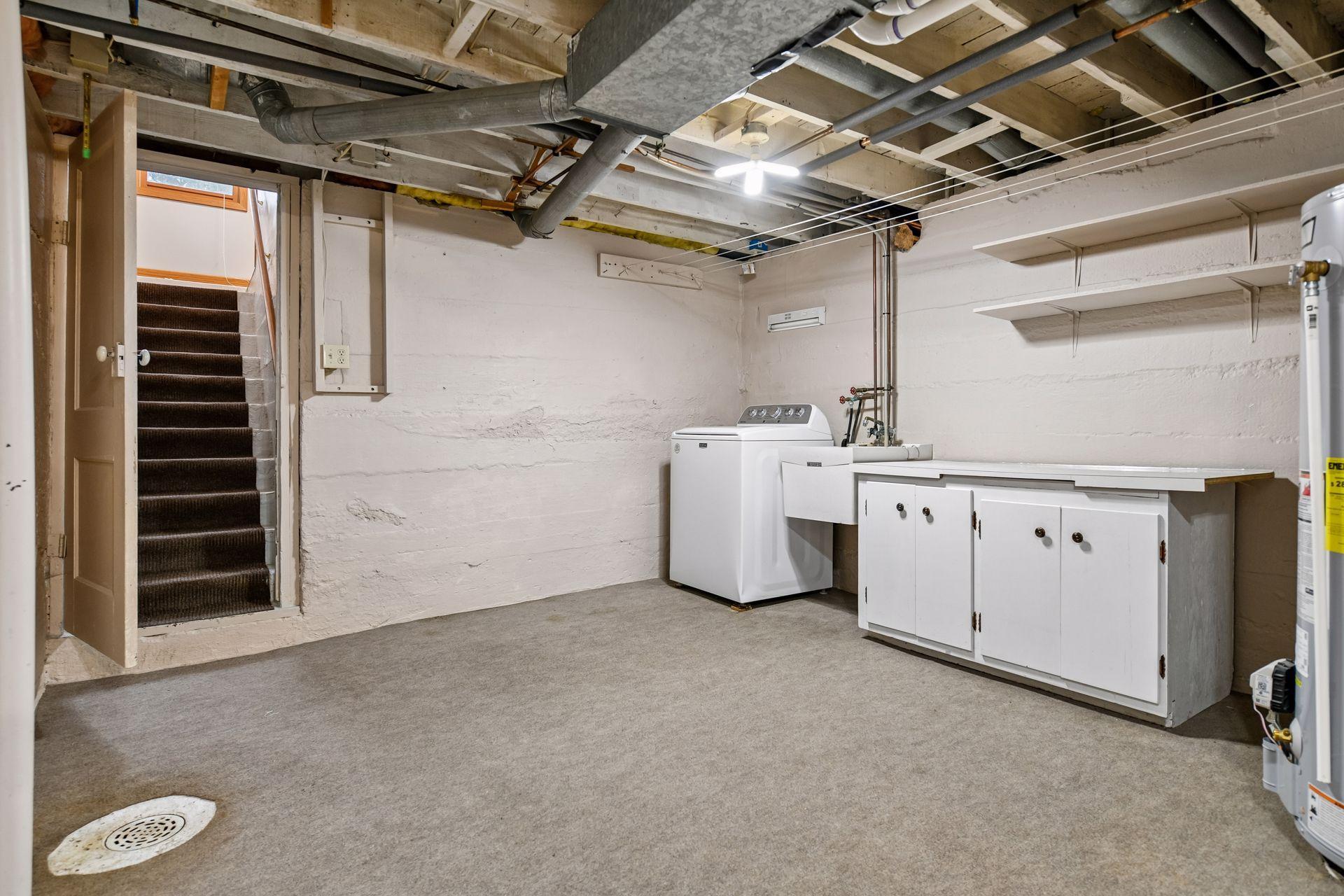 The lower level features a bright laundry room with a utility sink and folding counter.