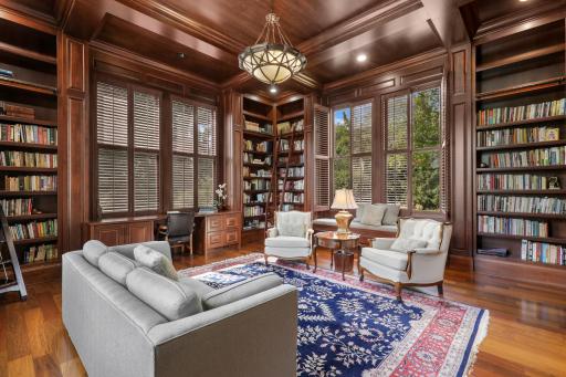Custom millwork takes center stage in this sophisticated library, with full-height bookcases, built-in benches, and plantation-shuttered windows defining the room.