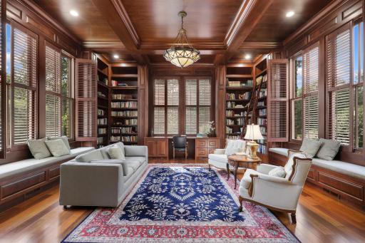 Custom millwork takes center stage in this sophisticated library, with full-height bookcases, built-in benches, and plantation-shuttered windows defining the room.