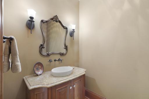 A beautifully appointed main-level powder room is finished with marble countertops and refined details.
