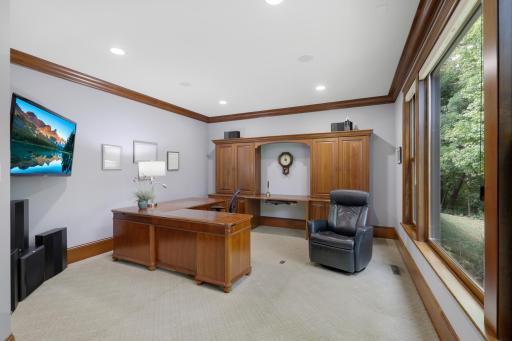 Expansive windows bring natural light into the generous office, while built-in credenzas provide elegant, thoughtfully integrated storage.