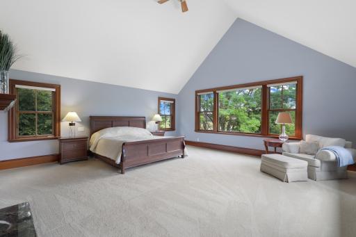 Expansive views and exceptional privacy define the generously sized primary bedroom, where a fireplace adds warmth and character. The luxurious ensuite offers a soaking tub, steam shower, and heated floors.