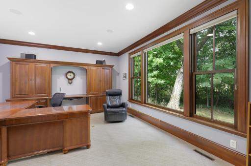 Expansive windows bring natural light into the generous office, while built-in credenzas provide elegant, thoughtfully integrated storage.