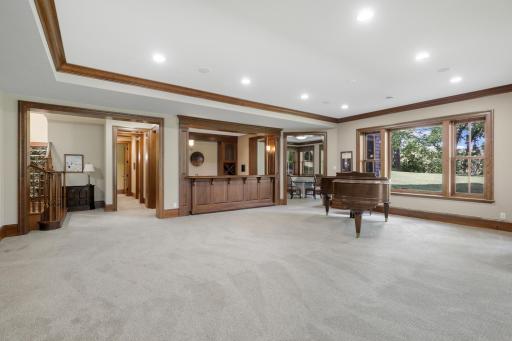 A substantial recreation room sits alongside a beautifully crafted full wet bar, featuring custom cabinetry and exceptional woodwork throughout.