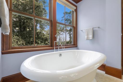 A generous soaking tub sits beside a large window, creating a retreat filled with natural light.