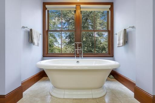 A generous soaking tub sits beside a large window, creating a retreat filled with natural light.