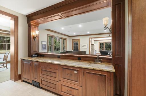 The full wet bar showcases beautifully detailed custom cabinetry and woodwork, bringing warmth and character to the lower-level entertaining space.
