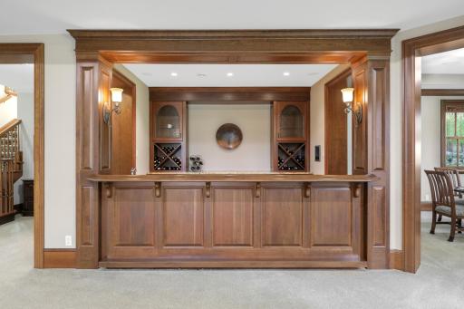 The full wet bar showcases beautifully detailed custom cabinetry and woodwork, bringing warmth and character to the lower-level entertaining space.