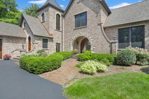 A welcoming path leads through the landscape to the stately arched front door.