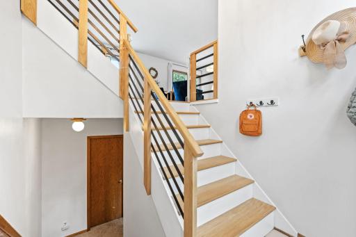 Entry stairway with wood treads, white risers, and a horizontal metal railing.