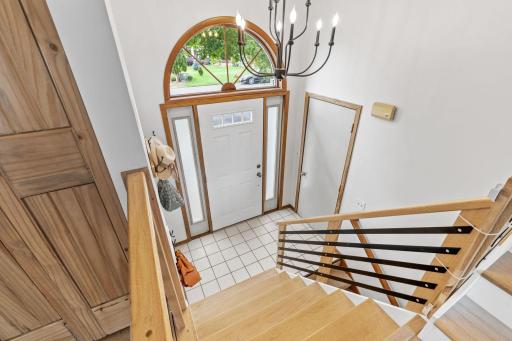 Split entry foyer with tile flooring, an arched transom window, and a beautiful chandelier overhead.