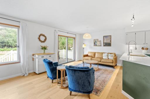 Open concept living room with white oak engineered hardwood flooring, a sliding glass door to the deck, and plenty of natural light.