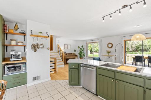 Open shelving, a built in appliance niche, and sightlines to the living room, backyard and stairway to the bedrooms.